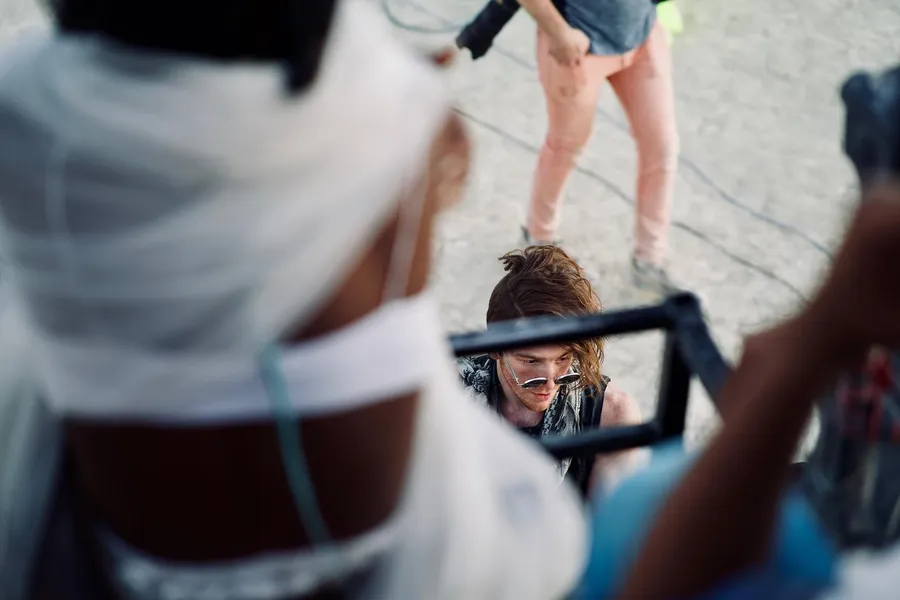 A smiling person seen through a rectangular frame between two foreground figures