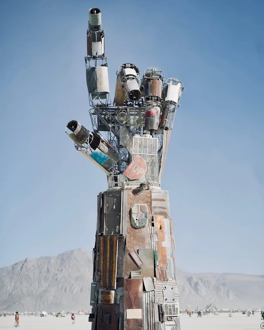 A towering mechanical hand sculpture points one finger toward the sky