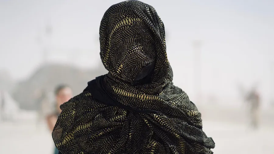 A person is wrapped from head to shoulders in black and gold mesh