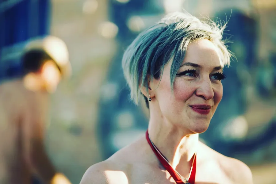 Profile portrait of a person with short turquoise and white hair