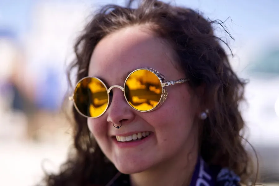 Close portrait of a smiling woman wearing round yellow mirrored sunglasses