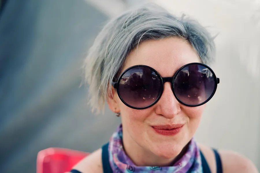 Close portrait of a woman with short silver hair and oversized round black sunglasses