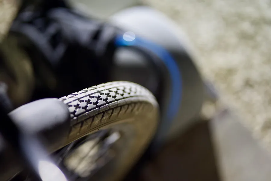 Shallow-focus close-up of a patterned bicycle tire with another wheel blurred behind