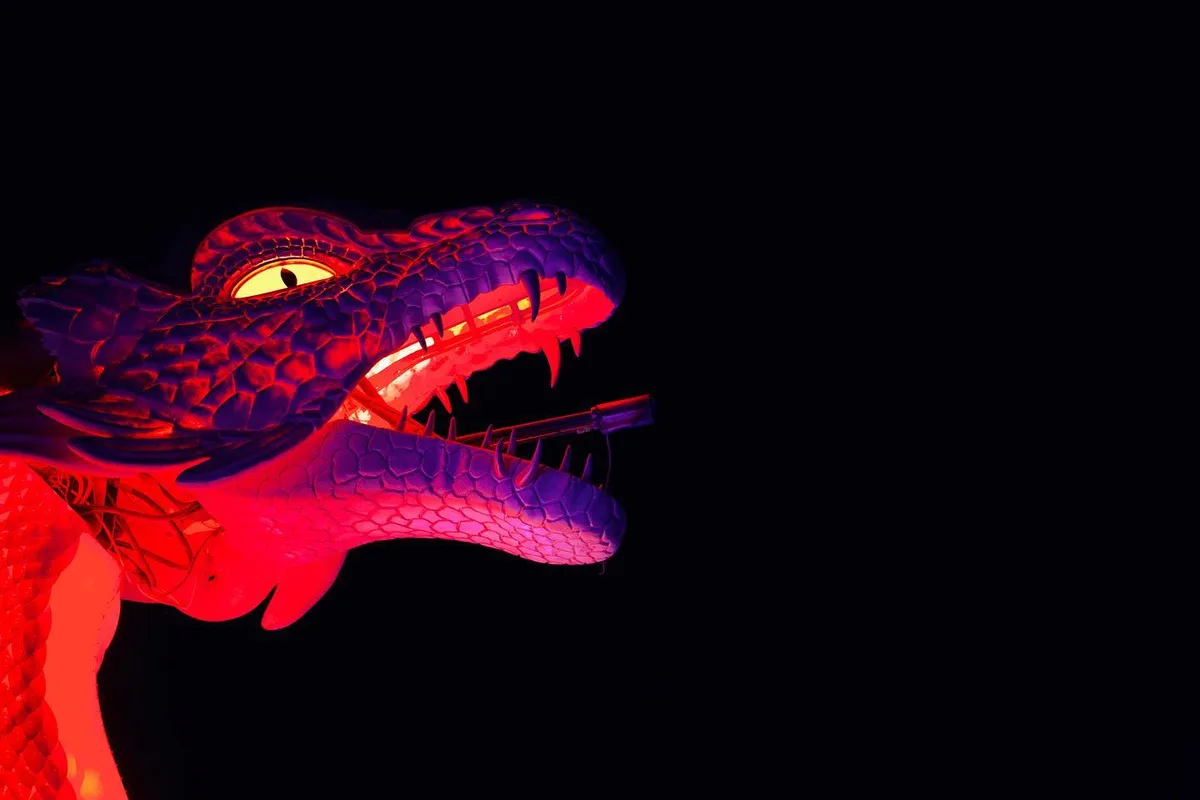 An illuminated dragon head glows red and purple against the night sky