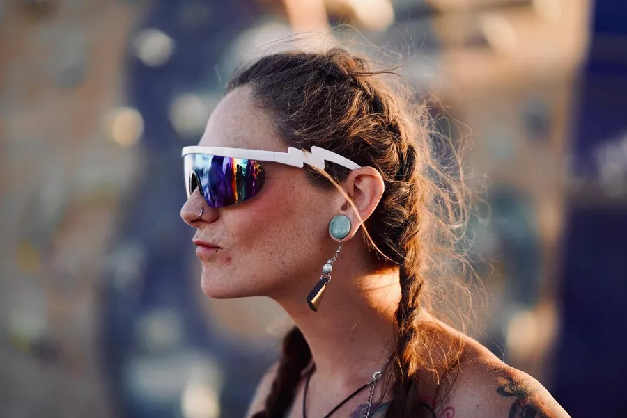 A woman in mirrored sunglasses shown in profile on the playa