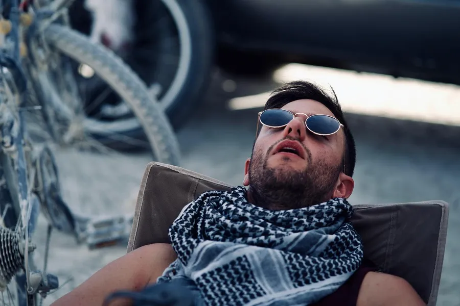 A man in sunglasses reclines in a chair on the playa
