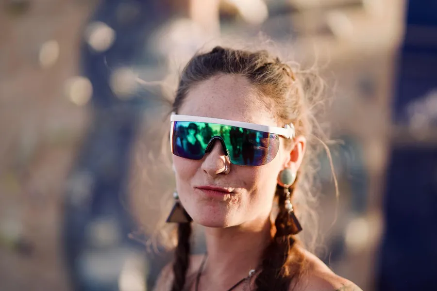 A woman wearing a mirrored visor smiles on the playa
