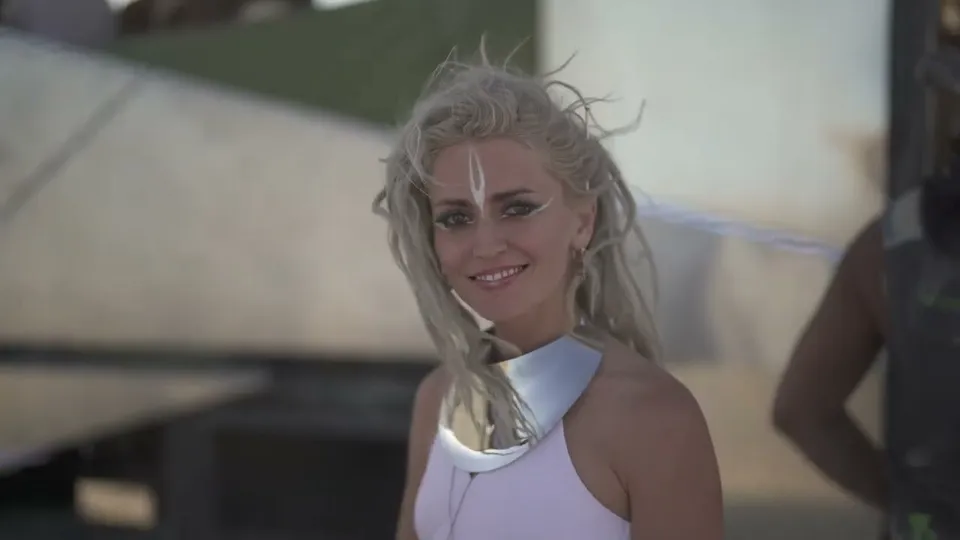 A smiling woman with platinum braids and white face paint at Burning Man